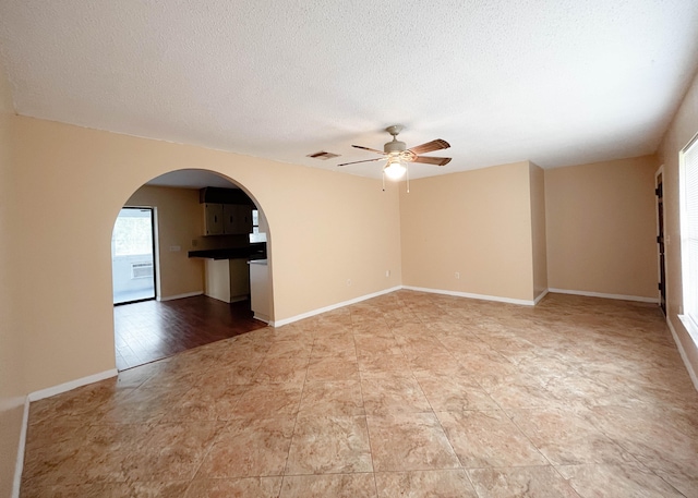 empty room with ceiling fan, light wood-type flooring, and a textured ceiling