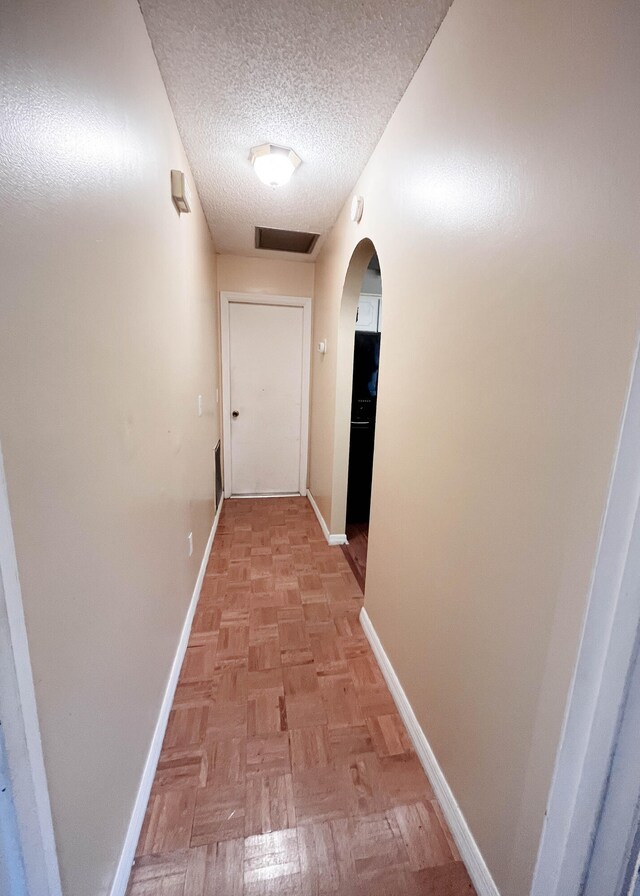 corridor featuring a textured ceiling and light parquet floors