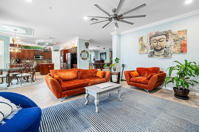 living room with light tile patterned flooring, ceiling fan, a textured ceiling, and ornamental molding