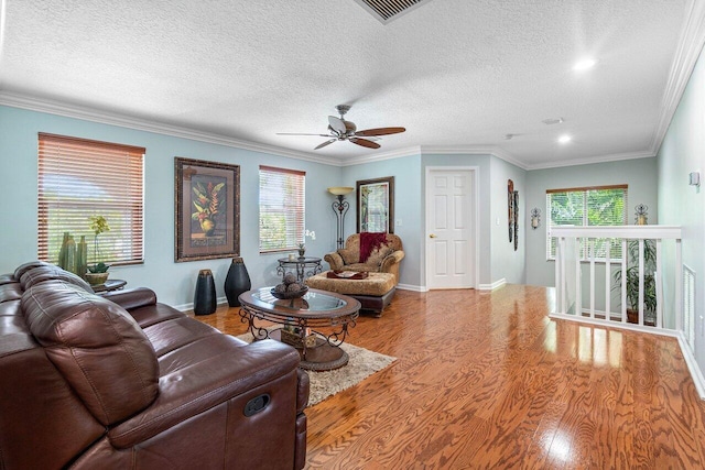 living room featuring light hardwood / wood-style floors, a textured ceiling, crown molding, and plenty of natural light