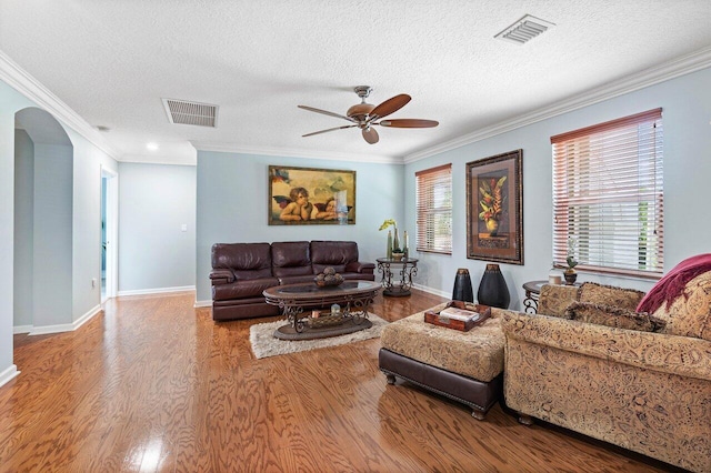 living room featuring a textured ceiling, a wealth of natural light, ornamental molding, and hardwood / wood-style flooring