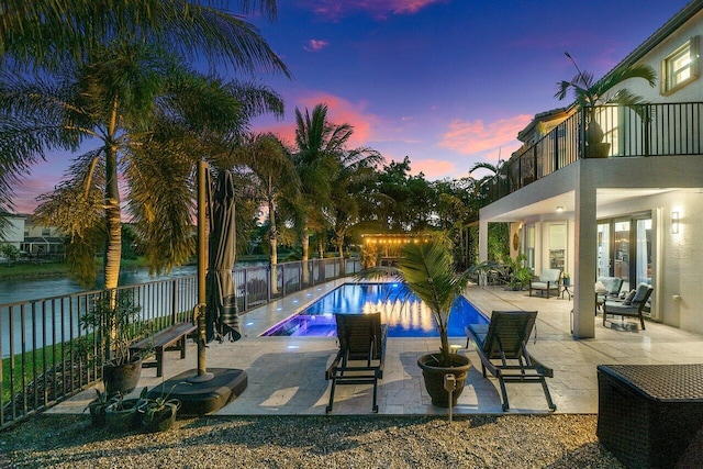 pool at dusk featuring a patio area