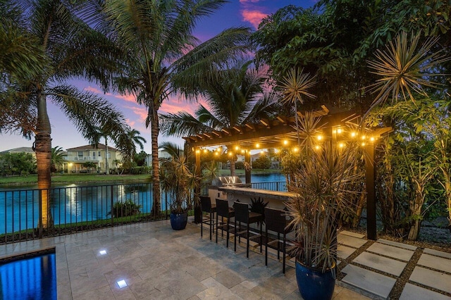 patio terrace at dusk with a bar and a water view