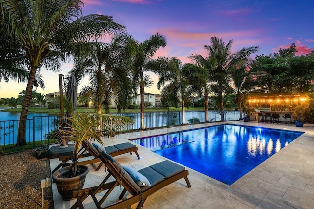 pool at dusk with a water view and a patio