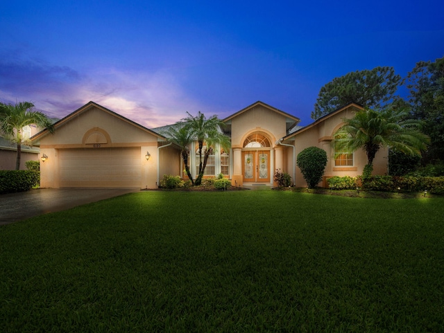 view of front facade with a garage, a lawn, and french doors