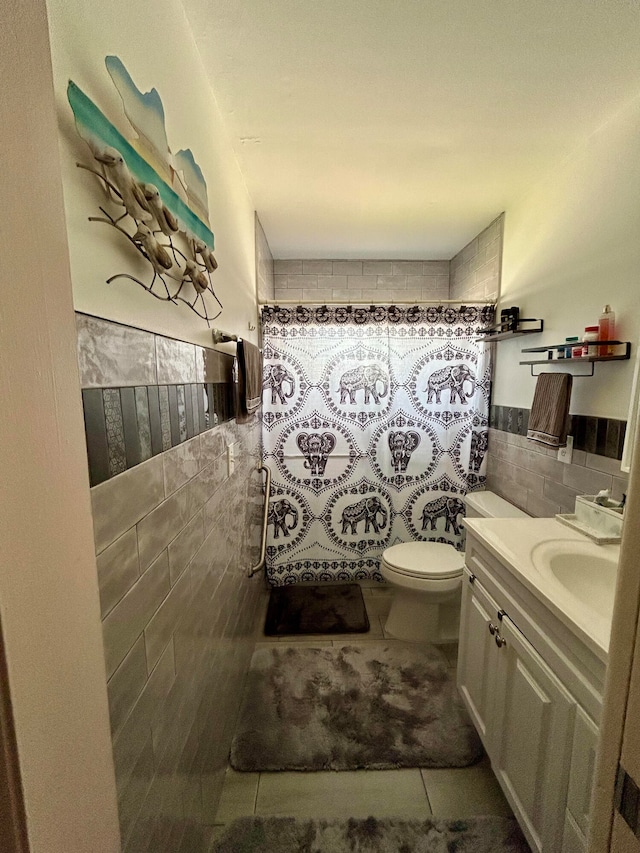 bathroom featuring tasteful backsplash, tile walls, tile patterned flooring, toilet, and vanity