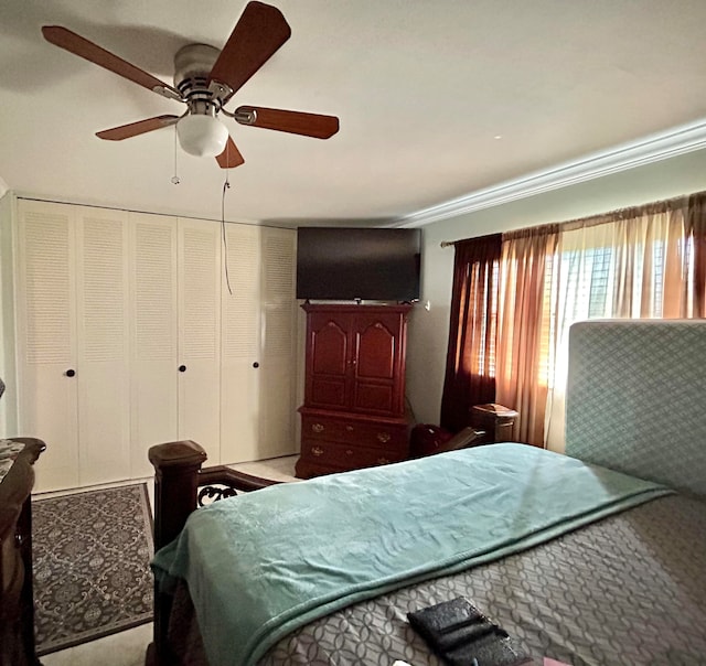 carpeted bedroom featuring crown molding, a closet, and ceiling fan