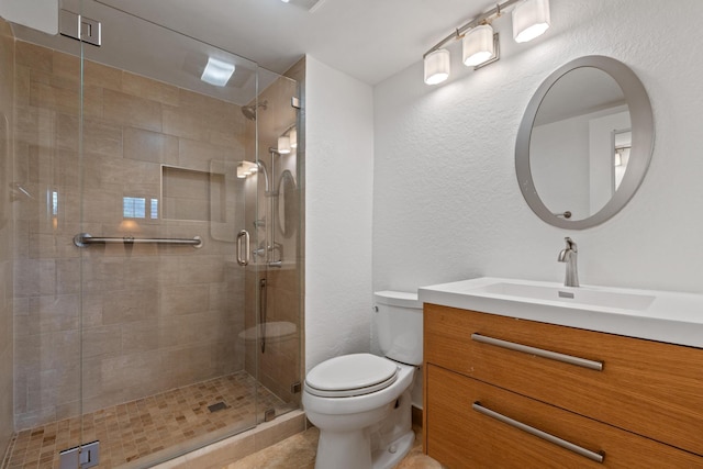 bathroom with a stall shower, a textured wall, vanity, and toilet