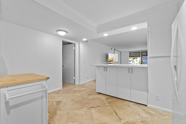 kitchen with freestanding refrigerator, white cabinets, light countertops, and baseboards