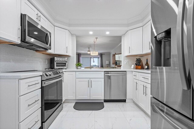 kitchen featuring appliances with stainless steel finishes, kitchen peninsula, crown molding, and white cabinetry