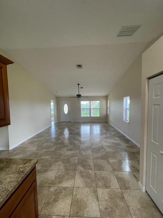 interior space featuring ceiling fan, light tile patterned floors, and vaulted ceiling