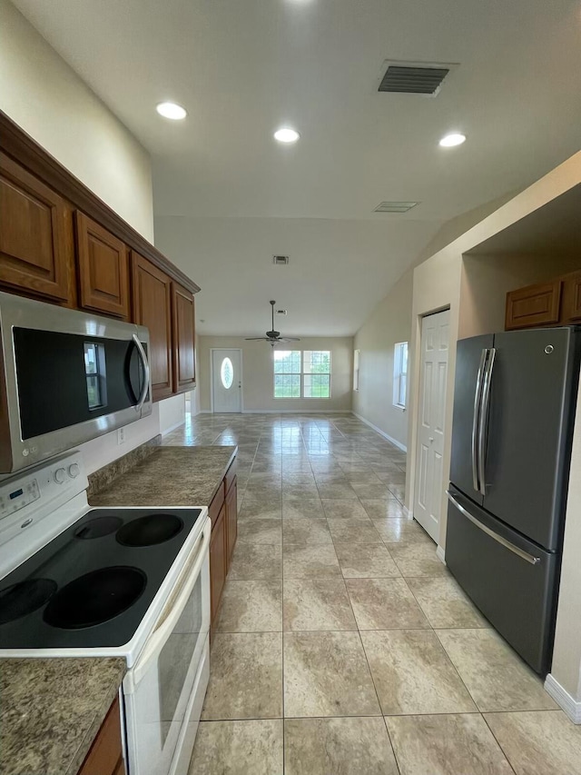 kitchen featuring appliances with stainless steel finishes, light stone counters, ceiling fan, and vaulted ceiling