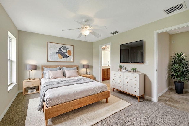 bedroom with ceiling fan, connected bathroom, and light colored carpet