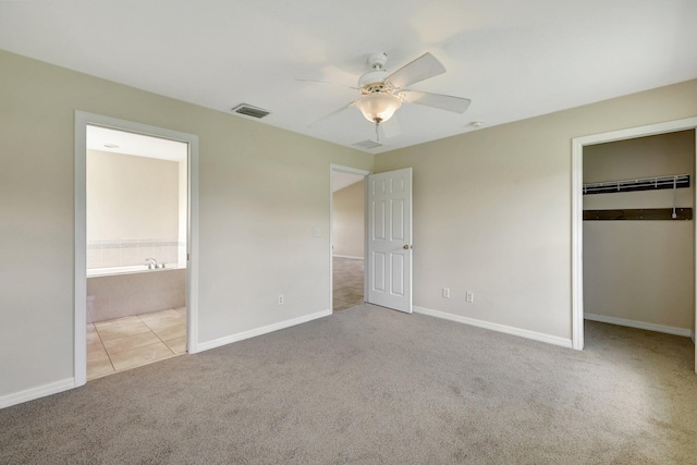 unfurnished bedroom featuring connected bathroom, ceiling fan, a closet, and light colored carpet