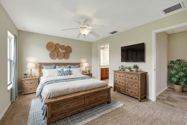 bedroom featuring ceiling fan, light colored carpet, and connected bathroom