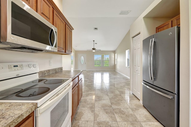 kitchen featuring lofted ceiling, ceiling fan, light tile patterned floors, and stainless steel appliances