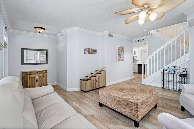 living room with a textured ceiling, light hardwood / wood-style flooring, ceiling fan, and ornamental molding