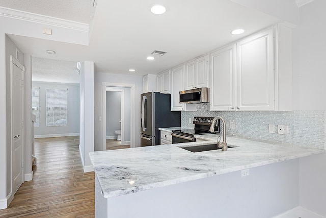 kitchen featuring stainless steel appliances, a sink, visible vents, white cabinetry, and tasteful backsplash