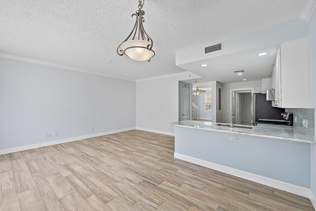 dining space with ornamental molding, a textured ceiling, and light hardwood / wood-style flooring