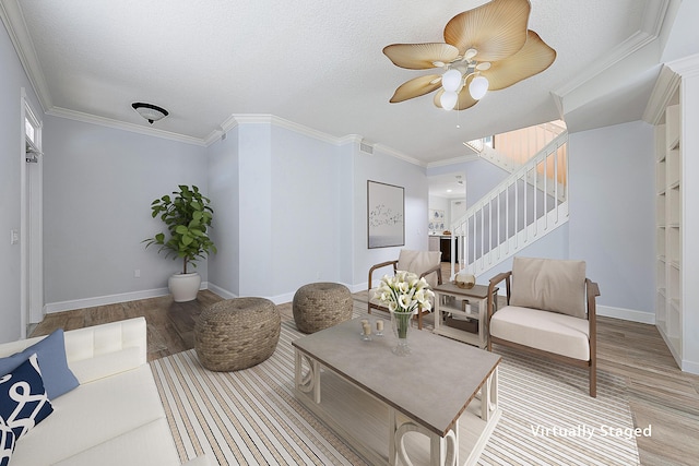 living area featuring stairs, crown molding, baseboards, and wood finished floors