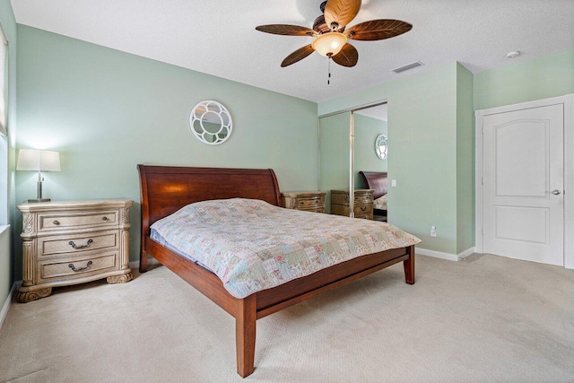 carpeted bedroom with ceiling fan, a closet, and a textured ceiling