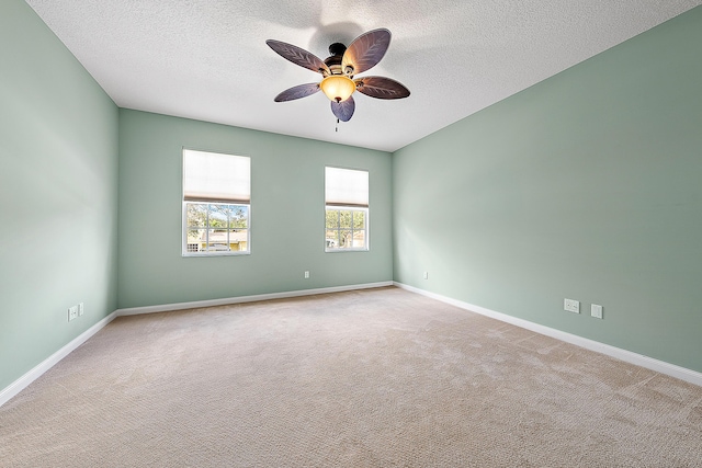 carpeted spare room with ceiling fan, baseboards, and a textured ceiling