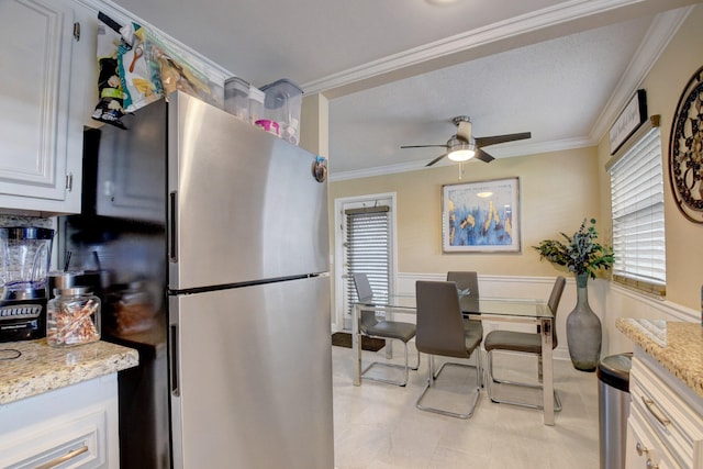 kitchen with light tile patterned flooring, light stone countertops, ceiling fan, and crown molding