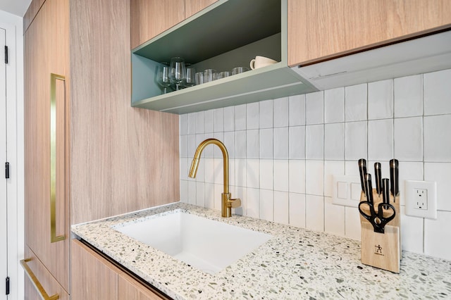 room details featuring light stone countertops, sink, light brown cabinets, and decorative backsplash