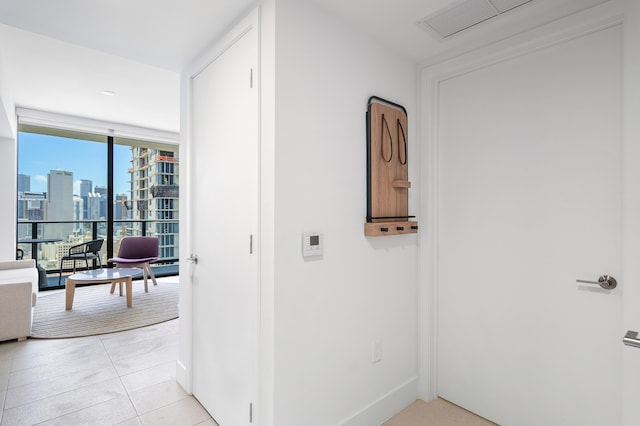 hallway with floor to ceiling windows and light tile patterned floors