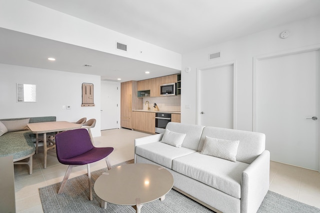 living room featuring sink and light tile patterned flooring