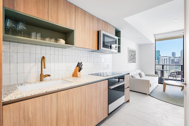 kitchen with wall oven, sink, tasteful backsplash, and light stone countertops