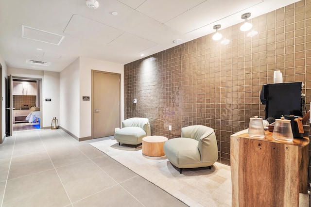 living area with light tile patterned floors and tile walls