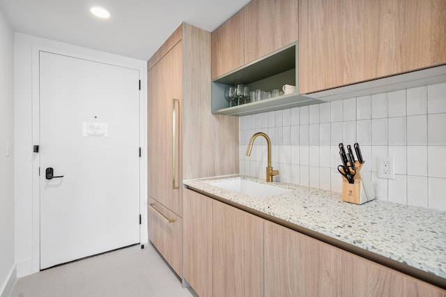 kitchen featuring sink, light brown cabinets, backsplash, and light stone counters