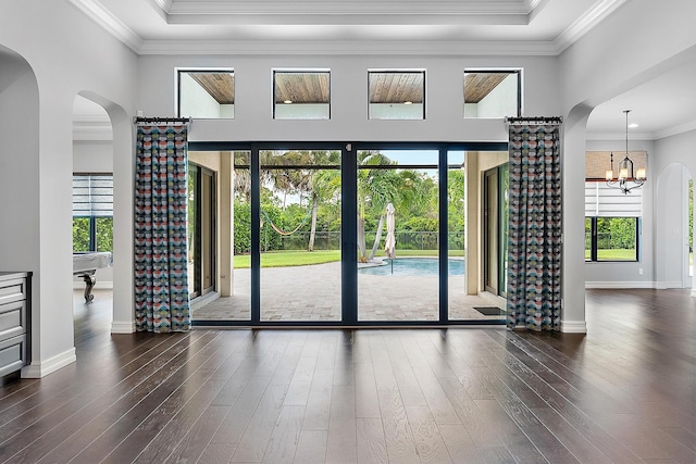 doorway featuring hardwood / wood-style floors, crown molding, an inviting chandelier, and plenty of natural light