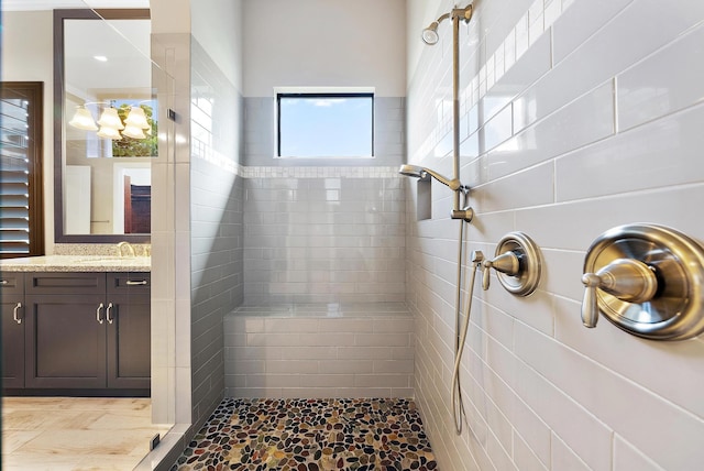 bathroom with a tile shower and vanity