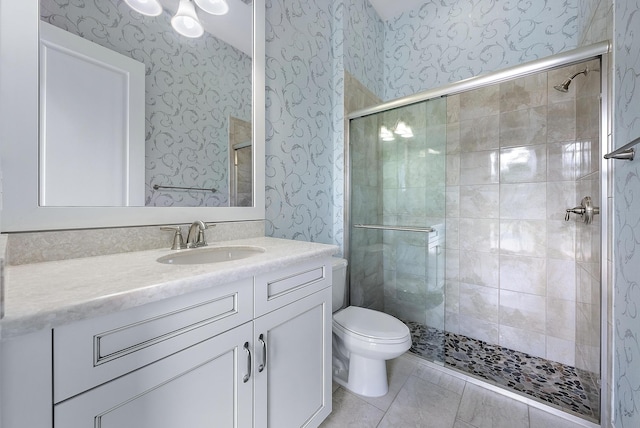 bathroom with tile patterned floors, a shower with shower door, vanity, and toilet