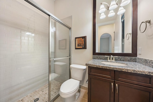 bathroom featuring a shower with shower door, toilet, vanity, and tile patterned floors