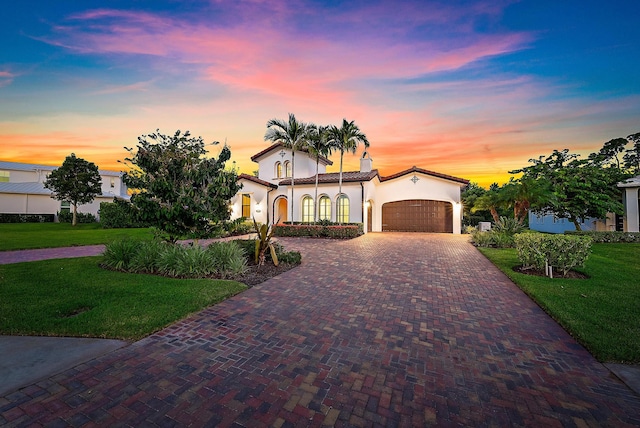 mediterranean / spanish-style home featuring a lawn and a garage