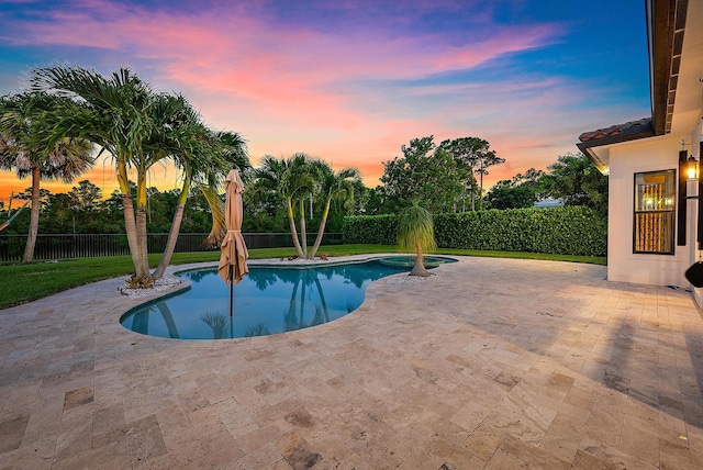 pool at dusk with a patio and a yard