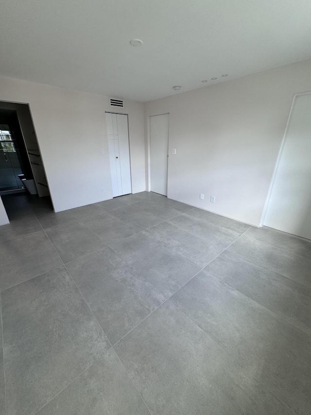 unfurnished bedroom with concrete flooring and visible vents