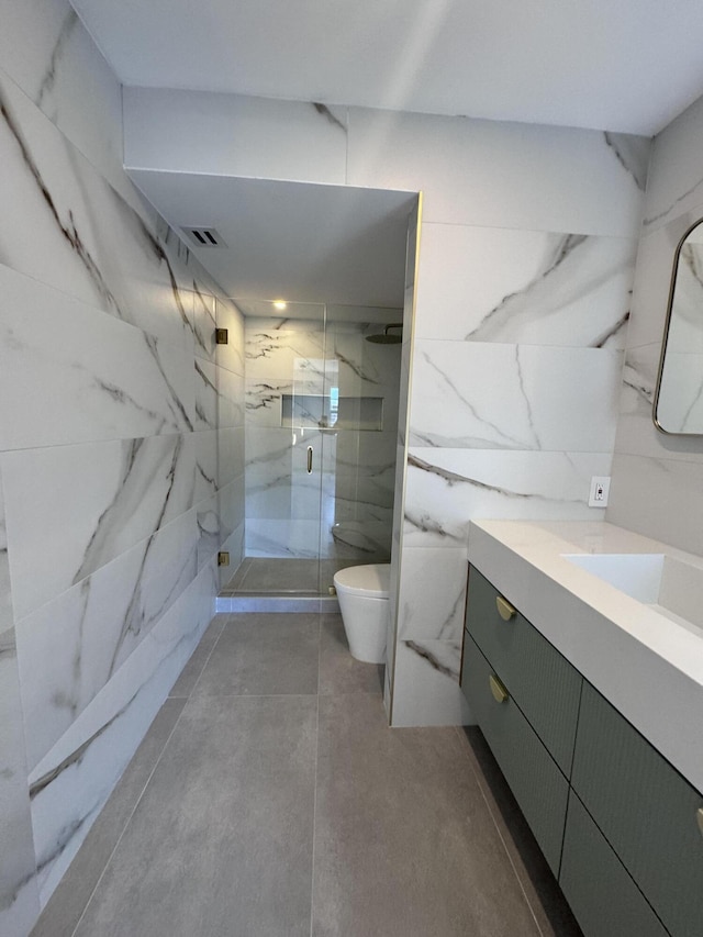 full bath featuring a marble finish shower, visible vents, toilet, vanity, and tile walls