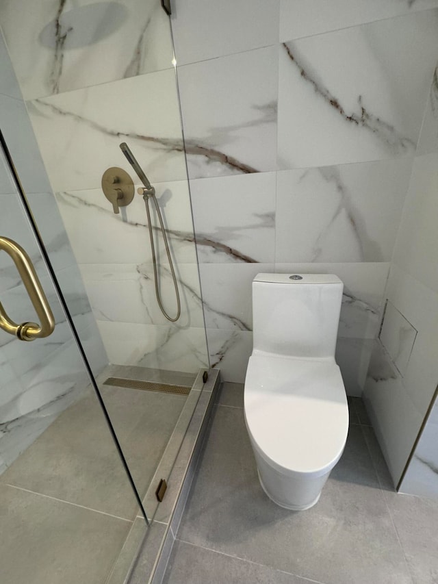 bathroom featuring a shower, tile patterned flooring, tile walls, and toilet