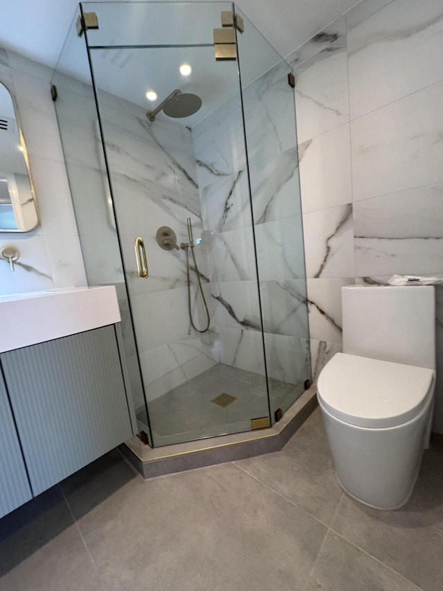 bathroom featuring toilet, a marble finish shower, vanity, and tile walls