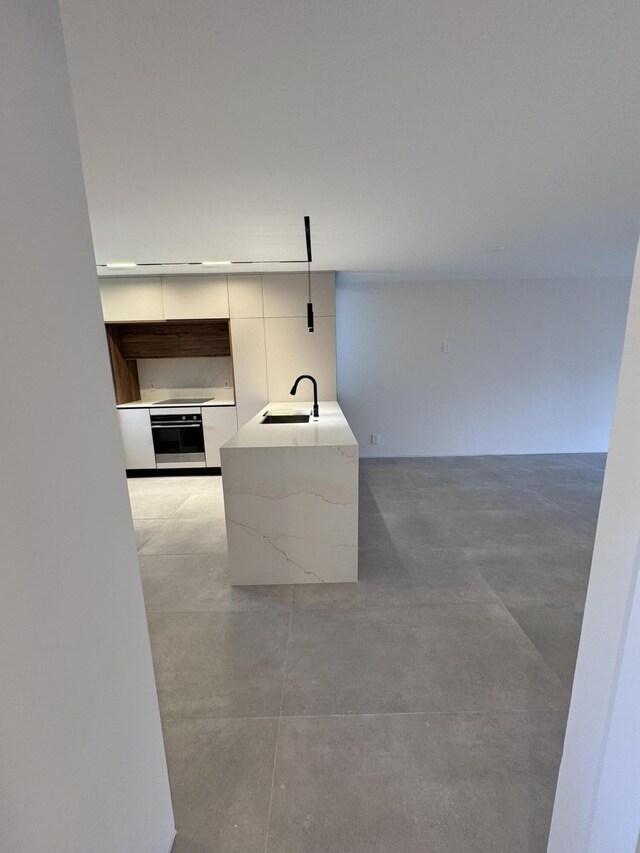 kitchen featuring sink, decorative light fixtures, white cabinets, and stainless steel oven