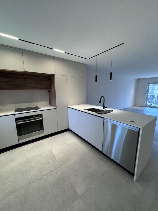 kitchen with stainless steel appliances, light countertops, a sink, and modern cabinets