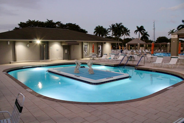 pool at dusk featuring a patio area