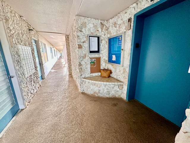 hallway featuring carpet and a textured ceiling