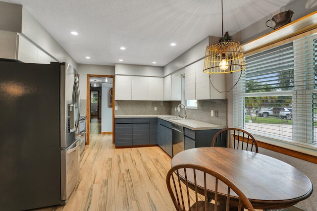 kitchen featuring appliances with stainless steel finishes, light hardwood / wood-style floors, white cabinetry, gray cabinets, and decorative light fixtures