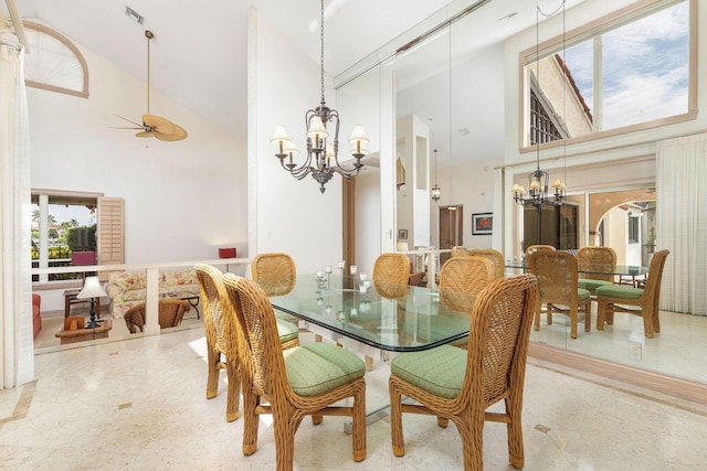 dining area featuring ceiling fan with notable chandelier and high vaulted ceiling