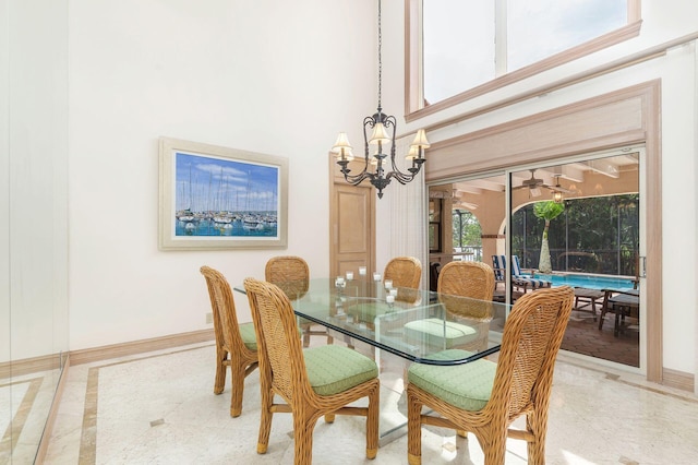 dining space with a towering ceiling and an inviting chandelier